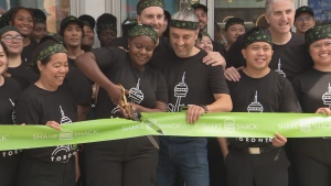 Shake Shack employees are shown cutting a ribbon outside the fast food chain's first Canadian location in downtown Toronto on June 13, 2024. (CP24)