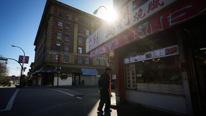 A pedestrian pauses outside Money BBQ and Foods Enterprises in Chinatown, in Vancouver, on Tuesday, March 28, 2023. THE CANADIAN PRESS/Darryl Dyck