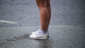 Water pours along a pedestrian on a sidewalk amid heavy rain. THE CANADIAN PRESS/Justin Tang