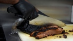 A line cook slices beef brisket at a barbecue restaurant in Cincinnati on June 12, 2024. (Joshua A. Bickel/AP Photo)