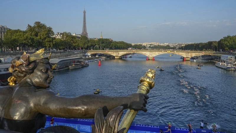 Athletes dive and swim in the Seine River from the Alexander III bridge on the first leg of the women's triathlon test event for the Olympics Games in Paris, Aug. 17, 2023. (AP Photo/Michel Euler, File)
