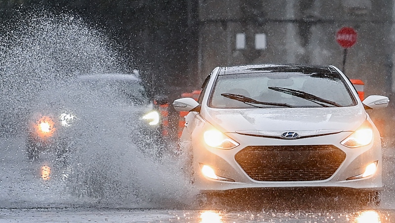 A motorist makes their way along a street through pooling water during heavy rain in Montreal, Saturday, October 7, 2023.THE CANADIAN PRESS/Graham Hughes