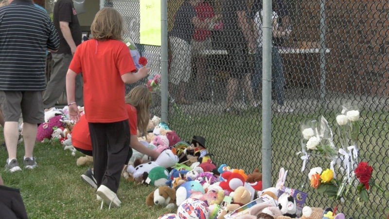 Friends of a Harrow family of four, who were found dead on Jun. 20, lay flowers along the fence at Harrow Soccer Complex during a vigil three days later. (Sanjay Maru/CTV News Windsor) 