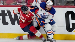 Edmonton Oilers forward Connor McDavid (97) dumps Florida Panthers forward Eetu Luostarinen (27) against the boards as he turns with the puck during second period game 7 of the NHL Stanley Cup finals in Sunrise, Fla., on Monday, June 24, 2024. THE CANADIAN PRESS/Nathan Denette