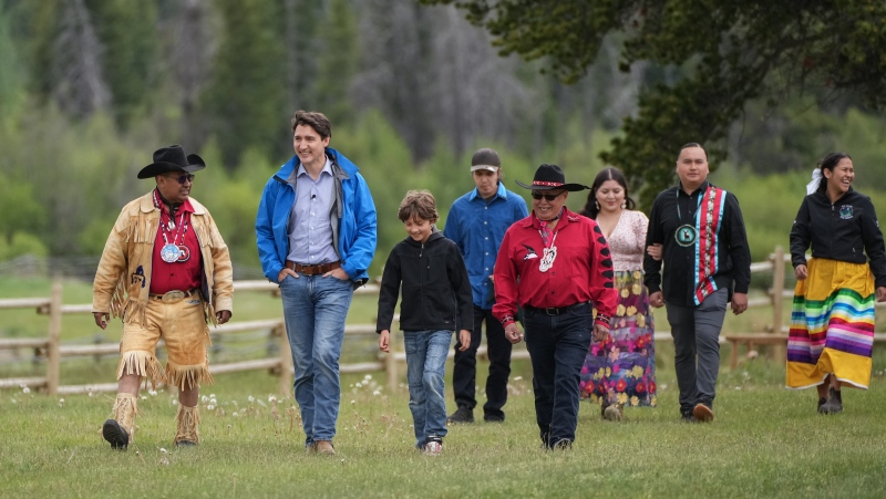 Prime Minister Justin Trudeau, second left, and his son Hadrien, 10, walk with Chief Roger William, left, and Chief Otis Guichon, front right, as they arrive for community celebrations to mark the 10th anniversary of the Tsilhqot'in decision, in Nemaiah Valley, B.C., on Wednesday, June 26, 2024. In 2014, the Supreme Court of Canada granted Tsilhqot'in aboriginal title to more than 1,750 square kilometres of land in the Nemiah Valley. THE CANADIAN PRESS/Darryl Dyck