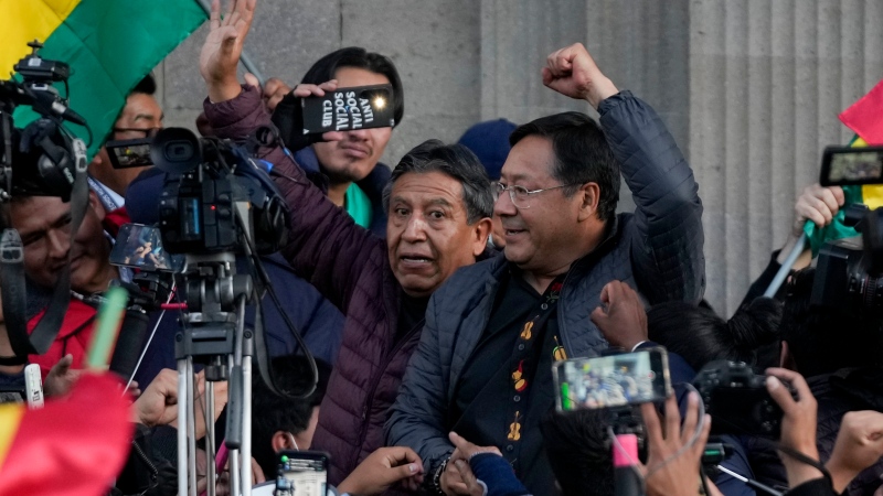 Bolivian President Luis Arce raises a clenched fist, with Vice-President David Choquehuanca, as they are surrounded by supporters and media in La Paz, Bolivia, Wednesday, June 26, 2024. (Juan Karita / AP Photo)