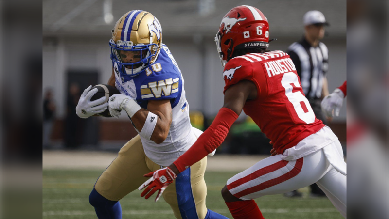 Winnipeg Blue Bombers' Nic Demski (10) runs the ball as Calgary Stampeders' Demerio Houston (6) closes in during first half CFL football action in Calgary, Alta., Saturday, June 29, 2024. THE CANADIAN PRESS/Jeff McIntosh