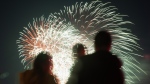 People watch as fireworks explode over LeBreton Flats area during Canada Day celebrations in downtown Ottawa, on Saturday, July 1, 2023. (Spencer Colby / The Canadian Press)