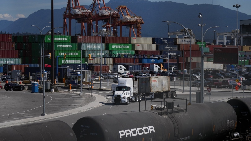 Transport trucks carry cargo containers at port in Vancouver, on Friday, July 14, 2023. A union representing ship and dock foremen in British Columbia has issued 72-hour strike notice against their employer. (Darryl Dyck / The Canadian Press)