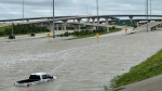 A vehicle is stranded in high waters on a flooded highway in Houston, on Monday, July 8, 2024, after Beryl came ashore in Texas as a hurricane and dumped heavy rains along the coast. (AP Photo/Juan A. Lozano)
