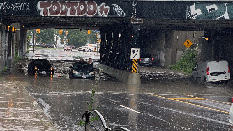 People stuck on top of car as flooding under bridge near High Park, Wednesday, July 15, 2024.