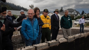 Jasper Mayor Richard Ireland, second left in blue, looks at what is left of his home of 67 years with federal Minister of Emergency Preparedness Harjit Sajjan, left to right, & Premier Danielle Smith, and Minister of Forestry and Parks Todd Loewen in Jasper, Alta., on Friday, July 26, 2024. THE CANADIAN PRESS/Amber Bracken