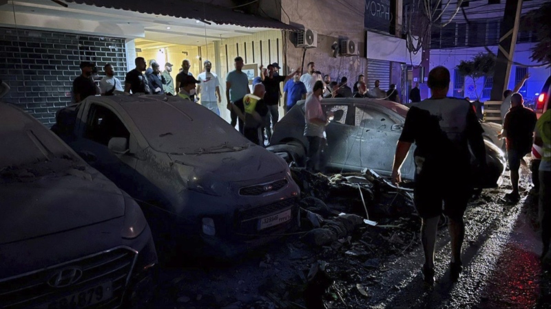 People inspect damaged cars in the southern suburbs of Beirut, Lebanon, Tuesday, July 30, 2024. An Israeli airstrike hit Hezbollah's stronghold south of Beirut Tuesday evening causing damage, a Hezbollah official and the group's TV station said. (AP Photo/Hussein Malla)