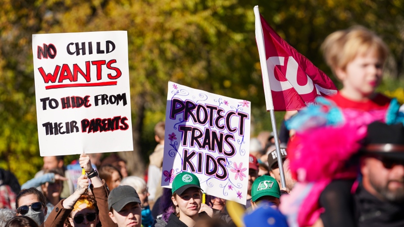 People hold signs while attending rally against the Saskatchewan government's proposed legislation on pronoun policy in front of Saskatchewan legislature in Regina, on Tuesday, October 10, 2023. THE CANADIAN PRESS/Heywood Yu