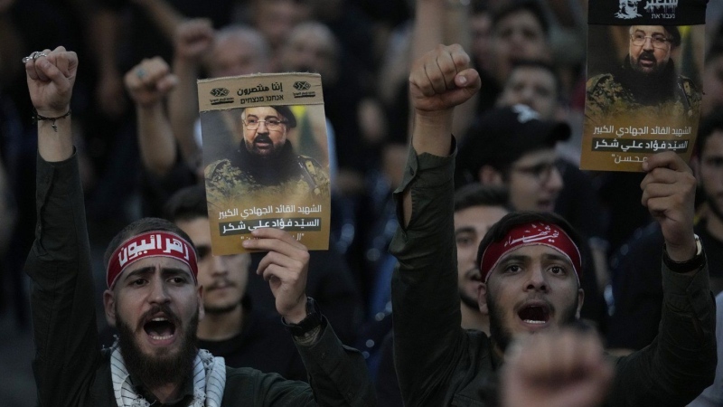 Hezbollah supporters shout slogans and hold up portraits that show the top commander Fouad Shukur, who was killed by an Israeli airstrike on Tuesday, July 30, during his funeral procession in a southern suburb of Beirut, Lebanon, Aug. 1, 2024. (AP Photo/Hussein Malla, File)