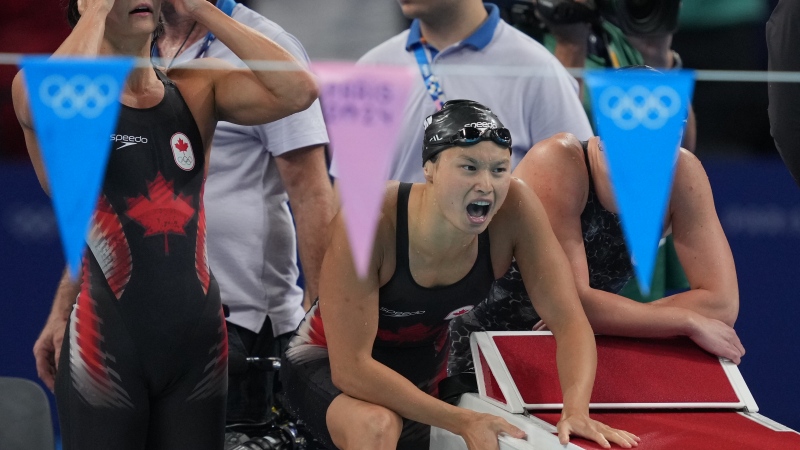 Canada's Kylie Masse (left to right), Maggie Mac Neil and Sophie Angus cheer on teammate Summer McIntosh in the pool on Sunday, Aug.4, 2024. (Source: THE CANADIAN PRESS/Christinne Muschi)