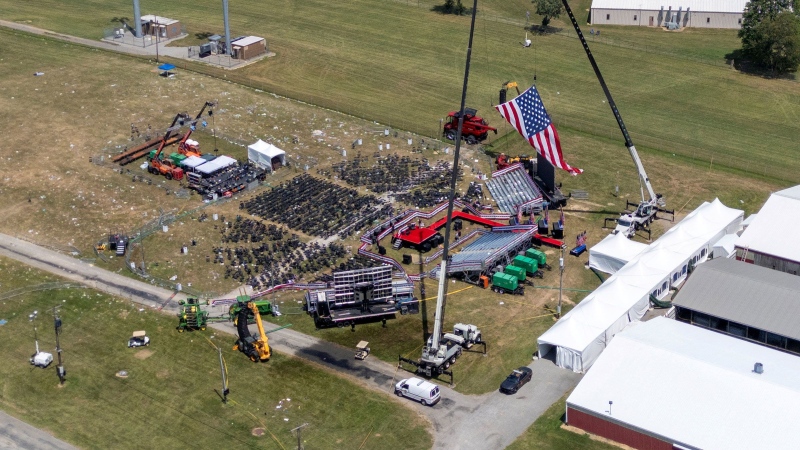 Stage where former U.S. President Donald Trump had been standing during an assassination attempt the day before, and the roof of a nearby building where a gunman was shot dead by law enforcement, in Butler, Pennsylvania, on July 14. (Carlos Osorio / Reuters via CNN Newsource)