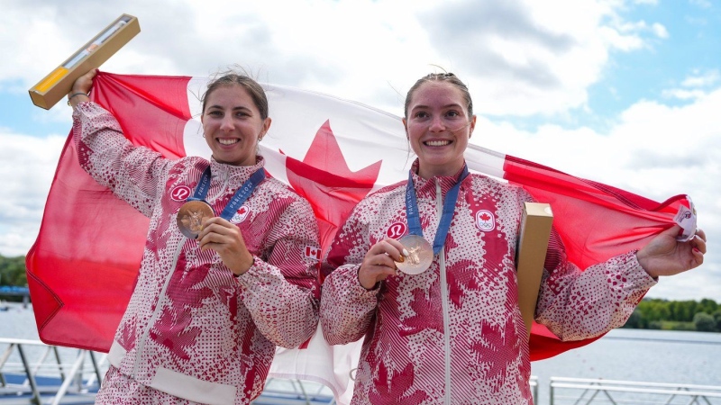 Canada's Sloan MacKenzie, right, and Katie Vincent pose with the flag after winning bronze medals in the women's canoe double 500m at the 2024 Summer Olympics, in Vaires-sur-Marne, France, Friday, Aug. 9, 2024. (Christinne Muschi / The Canadian Press)