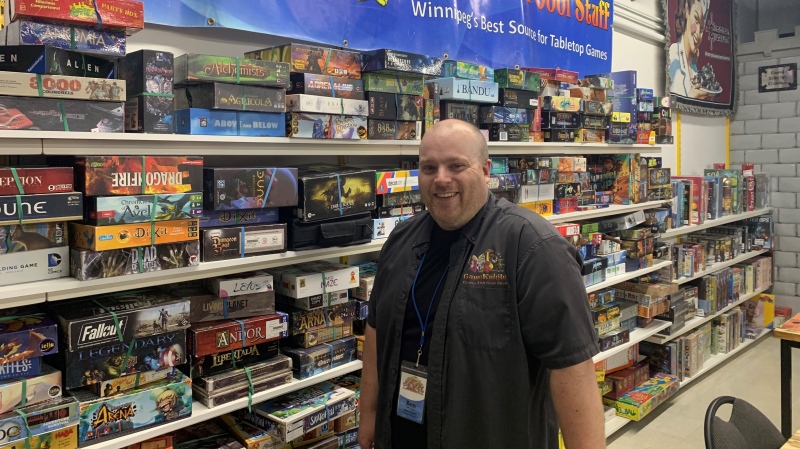 Ben Shantz, general manage of GameKnight in Winnipeg, poses in front of a wall of games people are able to rent. Shantz says modern board games are more diverse and creative than ever. (Charles Lefebvre/CTV News Winnipeg)