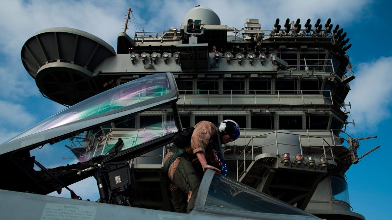 A pilot gets in the cockpit of an F/A-18 fighter jet on the deck of the USS Abraham Lincoln aircraft carrier in the Arabian Sea, Monday, June 3, 2019. (AP Photo/Jon Gambrell)