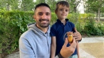 Cedric Devalaud and his son, Damian, with one of the wood carvings. (Gareth Dillistone / CTV News)