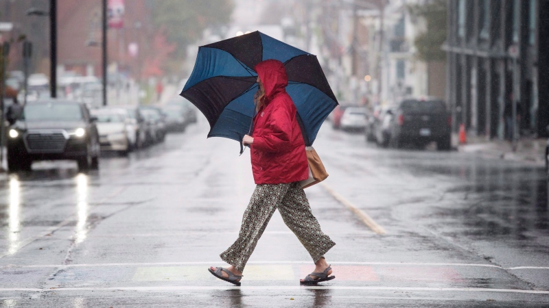 A pedestrian shields herself from the rain with an umbrella while walking downtown in Halifax on Monday, October 30, 2017. High winds and heavy rain has hit much of Atlantic Canada. THE CANADIAN PRESS/Darren Calabrese 