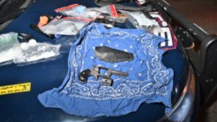 A handgun and several packages of suspected drugs lay splayed out on the hood of a Waterloo Regional Police Service vehicle. (Courtesy: Waterloo Regional Police Service)