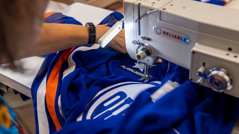 A Play Alberta logo being sewn on an Edmonton Oilers 2024/25 season home game jersey. (Oilers Entertainment Group)