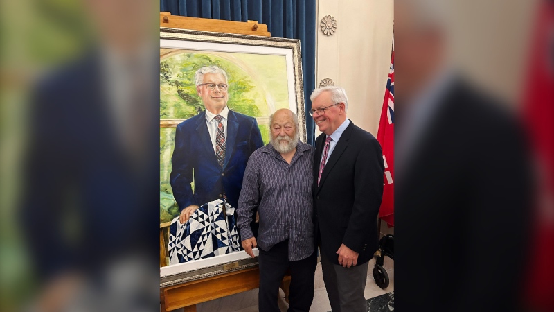 Former Manitoba premier Greg Selinger, right, poses for a photo with a supporter, next to a portrait of Selinger unveiled at the Manitoba legislature in Winnipeg on Tuesday, September 10, 2024. THE CANADIAN PRESS/Steve Lambert 