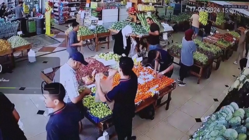 A man checks a pager before it explodes inside a grocery story in Beirut in this CCTV footage from Tuesday, Sept. 17, 2024.