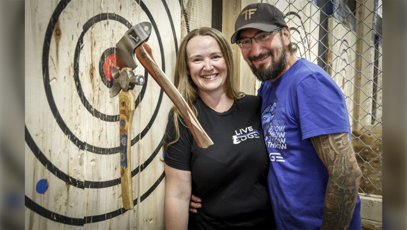 Nick and Kendra Kolomyja, a husband and wife team who run an axe and knife throwing business, lean on a target at their venue in Calgary, Monday, Sept. 16, 2024. THE CANADIAN PRESS/Jeff McIntosh