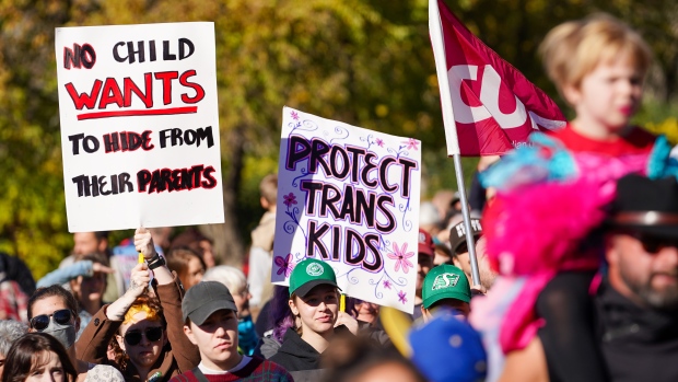 People hold signs while attending rally against the Saskatchewan government's proposed legislation on pronoun policy in front of Saskatchewan legislature in Regina, on Tuesday, October 10, 2023. THE CANADIAN PRESS/Heywood Yu