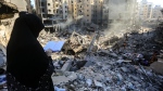 A woman reads the Koran in front of the rubble of buildings which were levelled on September 27 by Israeli strikes. (Photo by -/AFP via Getty Images)