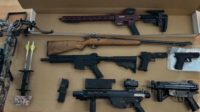 Various real and replica firearms and a crossbow are laid out on a table. (Courtesy: Guelph Police)