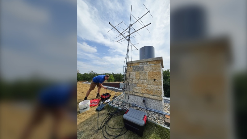 Workers install a Motus Wildlife Tracking System antenna atop the Qualico Family Centre in Assiniboine Park in September 2024. (Assiniboine Park Conservancy)