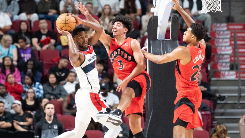 Washington Wizards guard Jared Butler (4) passes off as Toronto Raptors guard DJ Carton (3) and centre Ulrich Chomche (22) defend during second half NBA preseason basketball action In Montreal, Sunday, Oct. 6, 2024. (Christinne Muschi, The Canadian Press)