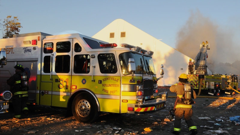 Firefighters stand beside a Kentville Volunteer Fire Department truck while smoke pours from a recycling depot in Kentville, N.S. (Bill Roberts)