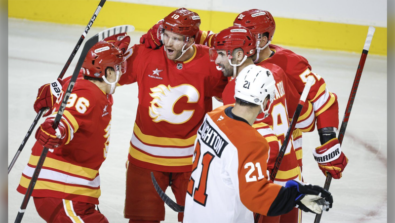 Philadelphia Flyers' Scott Laughton, right, skates past as Calgary Flames' Jonathan Huberdeau, second left, celebrates his goal with teammates during first period NHL hockey action in Calgary on Saturday, Oct. 12, 2024. THE CANADIAN PRESS/Jeff McIntosh