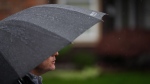 Environment Canada has ramped up its rainfall warnings in British Columbia, where Vancouver Island, metro Vancouver and the coastal regions of the province are expected to see major downpours. B.C. NDP Leader David Eby shields himself from the rain with an umbrella while speaking during a campaign stop in Coquitlam, B.C., on Friday, October 18, 2024. (Darryl Dyck / The Canadian Press)