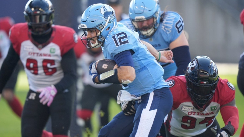 Toronto Argonauts quarterback Chad Kelly (12) rushes past Ottawa Redblacks defensive end Lorenzo Mauldin IV (94) to score a touchdown during first half CFL football action in Toronto on Saturday, Oct. 19, 2024. THE CANADIAN PRESS/Frank Gunn