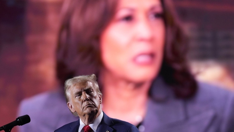 Republican presidential nominee former U.S. president Donald Trump watches as a video featuring Democratic presidential nominee U.S. Vice President Kamala Harris plays during a campaign event, Friday, Oct. 18, 2024 in Detroit. (AP Photo/Evan Vucci)