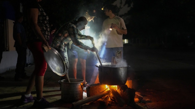 Residents prepare a soup over an open fire during a blackout following the failure of a major power plant in Havana, Cuba, Saturday, Oct. 19, 2024. (AP Photo/Ramon Espinosa)