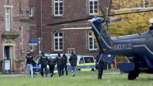 Police officers escort a Libyan national with suspected ties to the extremist group Islamic State who was allegedly planning an attack on the Israeli Embassy in Berlin, in Karlsruhe, Germany, Sunday Oct. 20, 2024. (Rene Priebe/dpa via AP)