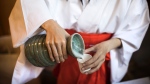 A Japanese attendant pours sake into a cup for visitors at the Koami Shinto shrine. (Behrouz Mehri / AFP / Getty Images via CNN Newsource)