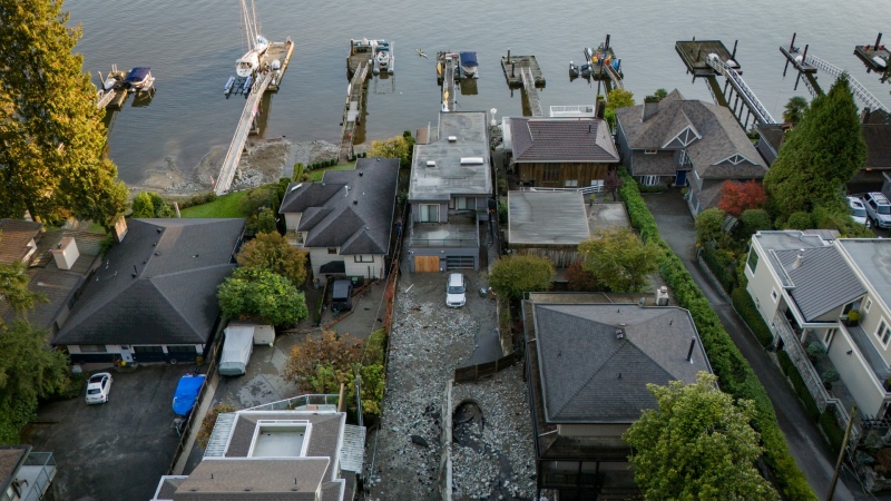 Multiple homes are seen surrounded by debris left by flooding from torrential rain from an atmospheric river weather system at Deep Cove in North Vancouver, on Tuesday, Oct. 22, 2024. Heavy rain isn't unusual for the community of Deep Cove, in North Vancouver, but when Ashifa Saferali saw an e-bike floating down the middle of the street she knew this storm was something different. (Ethan Cairns / The Canadian Press)