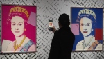 A man takes an image of a screen print depicting Queen Elizabeth II, one in a series of sixteen prints of four queens titled Reigning Queens, 1985, by Andy Warhol at museum Paleis Het Loo in Apeldoorn, Netherlands, Wednesday, Oct. 9, 2024. (AP Photo/Peter Dejong)