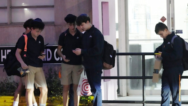 Students wait for their bus to school, Tuesday, Oct. 29, 2024, in Surfside, Fla. (AP Photo/Marta Lavandier)