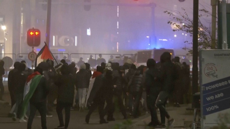 In this image taken from video, a group of pro-Palestinian protesters walk toward police line, with police vans driving in the background, near the soccer stadium in Amsterdam, Netherlands, Thursday, Nov. 7, 2024. (RTL Nieuws via AP)