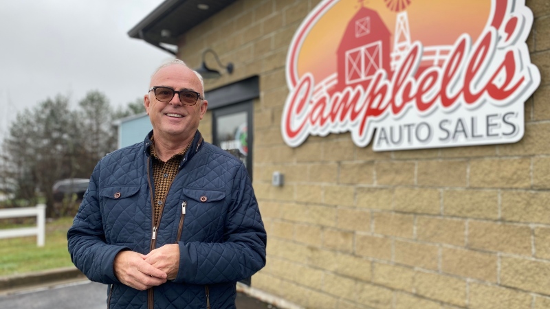 Andy Campbell is pictured outside of his business beside the sign for Campbell's Auto Sales.