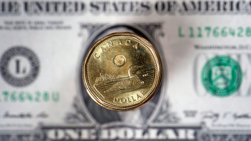 The Canadian dollar coin, the Loonie, is displayed over the U.S. dollar. (Paul Chiasson / The Canadian Press)